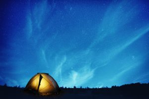 Illuminated yellow camping tent under many stars and at night